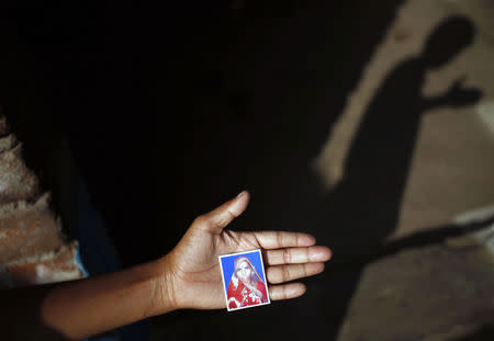 Narain, 8, holds a photo of his 30-year-old mother Phoolbai, who died after she underwent sterilization surgery at a government mass sterilisation "camp", at his home in Aamsena village in Bilaspur district, in the eastern Indian state of Chhattisgarh, November 13, 2014. REUTERS/Anindito Mukherjee