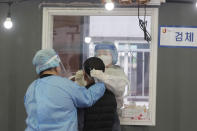 A medical worker in a booth takes a nasal sample from a man at a coronavirus testing site in Seoul, South Korea, Monday, April 12, 2021. The new mayor of South Korea's capital demanded swift approval of coronavirus self-testing kits, saying that his city urgently needs more tools to fight the pandemic and keep struggling businesses open. (AP Photo/Ahn Young-joon)