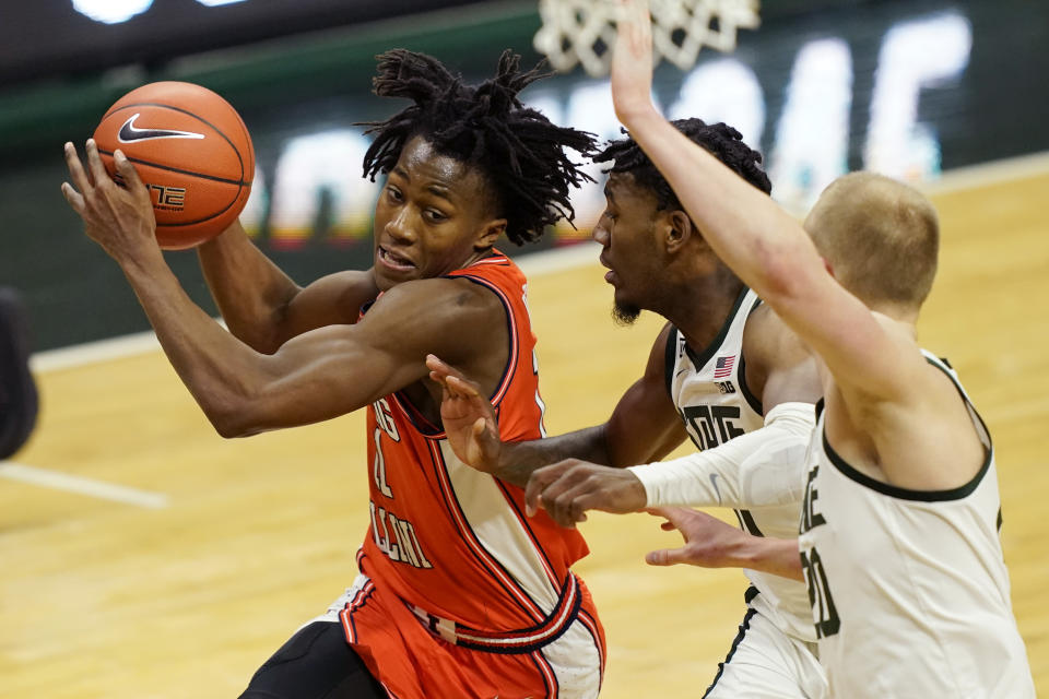 Illinois guard Ayo Dosunmu (11) drives as Michigan State guard A.J. Hoggard, center, and forward Joey Hauser defend during the first half of an NCAA college basketball game, Tuesday, Feb. 23, 2021, in East Lansing, Mich. (AP Photo/Carlos Osorio)