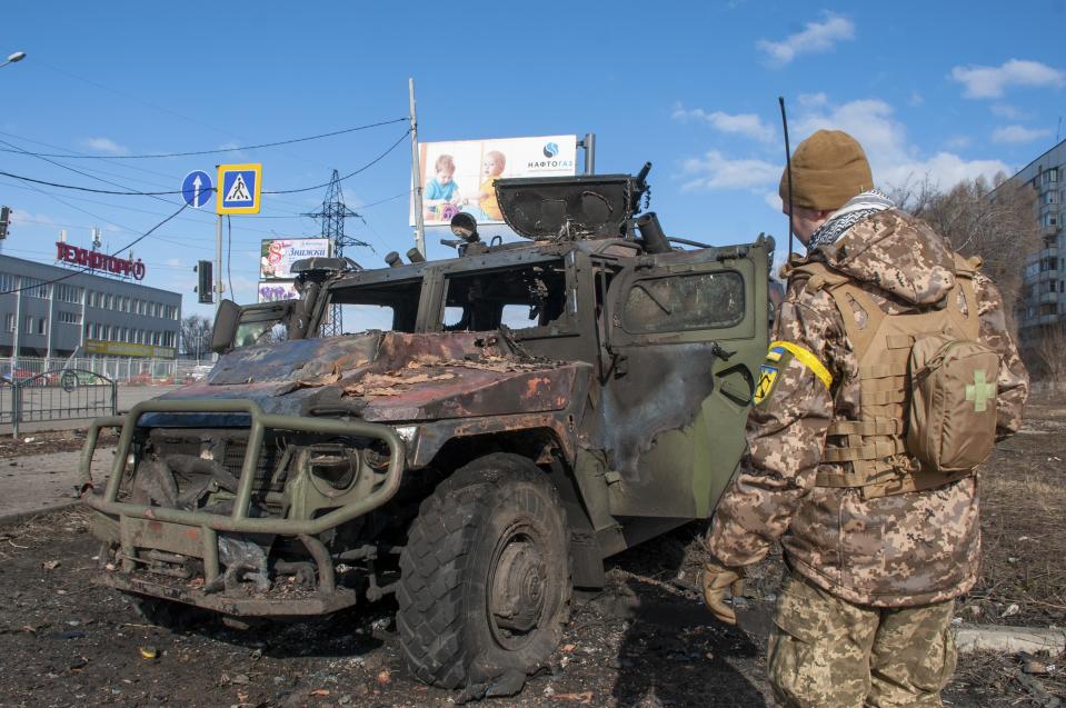 A Ukrainian soldier inspects a damaged military vehicle after fighting in Kharkiv, Ukraine, Sunday, Feb. 27, 2022. The city authorities said that Ukrainian forces engaged in fighting with Russian troops that entered the country's second-largest city on Sunday. (AP Photo/Marienko Andrew)