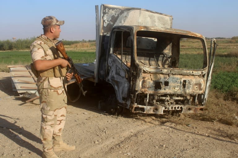 An Iraqi soldier inspects a burnt-out vehicle as troops gather on November 11, 2017, in readiness for an assault on the town of Rawa, the last in the country still held by the Islamic State group