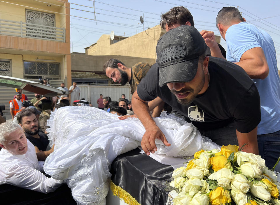 The coffin carrying Abbas Abdul Hussein, a 30-year-old victim of an artillery strike, is received by his family in Baghdad, to later lay him to rest in Najaf city, Thursday, July 21, 2022, in Baghdad, Iraq. Hussein was on his honeymoon, five days after his wedding, when at least four artillery shells struck the resort area of Barakh in the Zakho district in the Iraqi semi-autonomous Kurdish-run region, killing nine people. (AP Photo/Ali Jabar)