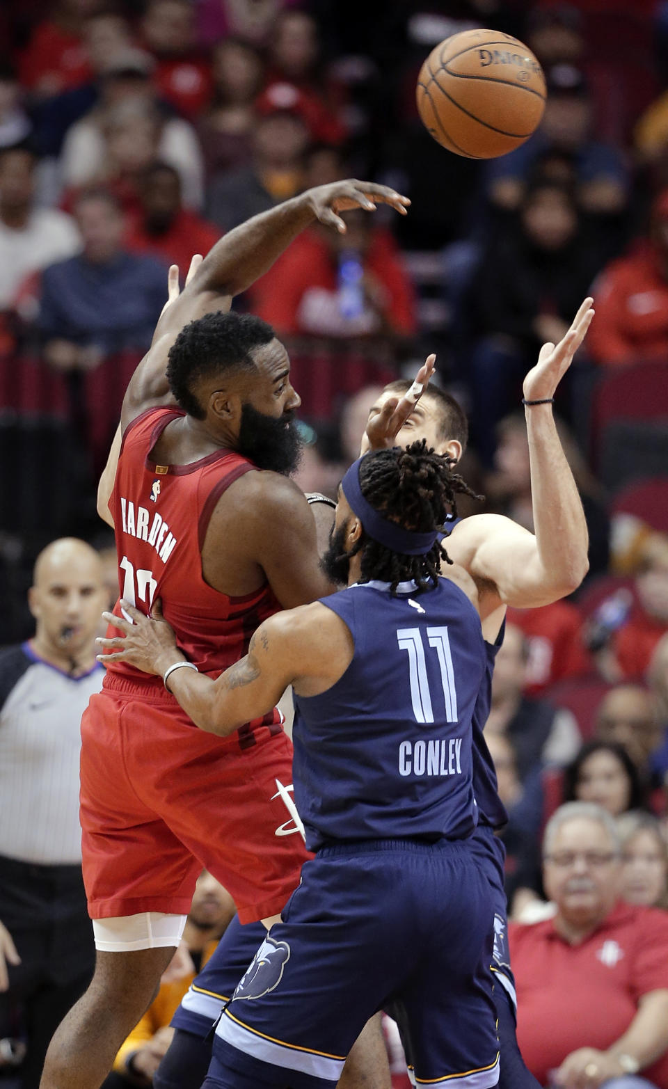 Houston Rockets guard James Harden (13) passes the ball over Memphis Grizzlies guard Mike Conley (11) and center Marc Gasol, back, during the first half of an NBA basketball game Monday, Dec. 31, 2018, in Houston. (AP Photo/Michael Wyke)