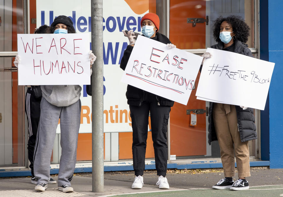 Women hold signs outside housing commission apartments under lockdown in Melbourne, Australia, on Monday, July 6, 2020. The leader of Australia’s most populous state says her government’s decision to close its border with hard-hit Victoria state marks a new phase in the country’s coronavirus pandemic. (AP Photo/Andy Brownbill)