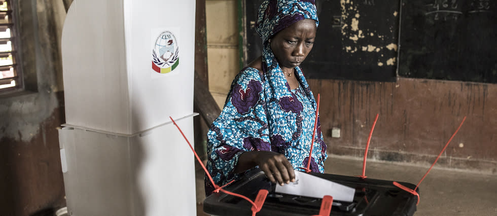 Une électrice dépose son bulletin de vote à l'isoloir d'une école lors du premier tour de l'élection présidentielle à Conakry le 18 octobre 2020. 
