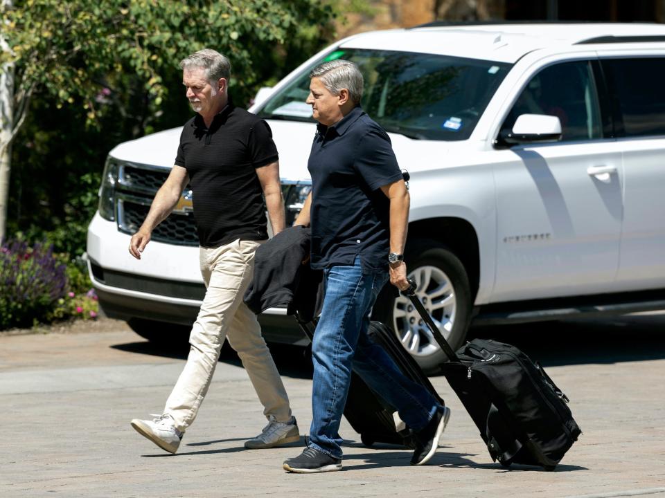 Reed Hastings and Ted Sarandos walk with suitcases at Sun Valley 2021