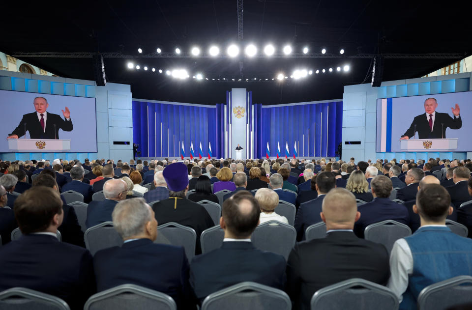 Putin is shown on large screens as he delivers his address. 