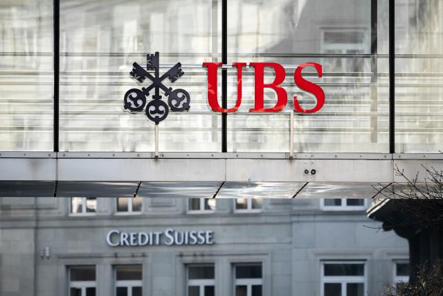 A sign and logo of Credit Suisse bank is seen beneath a sign of Swiss giant banking UBS in Zurich on March 20, 2023. - Shares in European banks sank on March 20, 2022 despite a buyout of Credit Suisse by Swiss lender UBS aimed at preventing a global banking crisis. (Photo by Fabrice COFFRINI / AFP) (Photo by FABRICE COFFRINI/AFP via Getty Images)