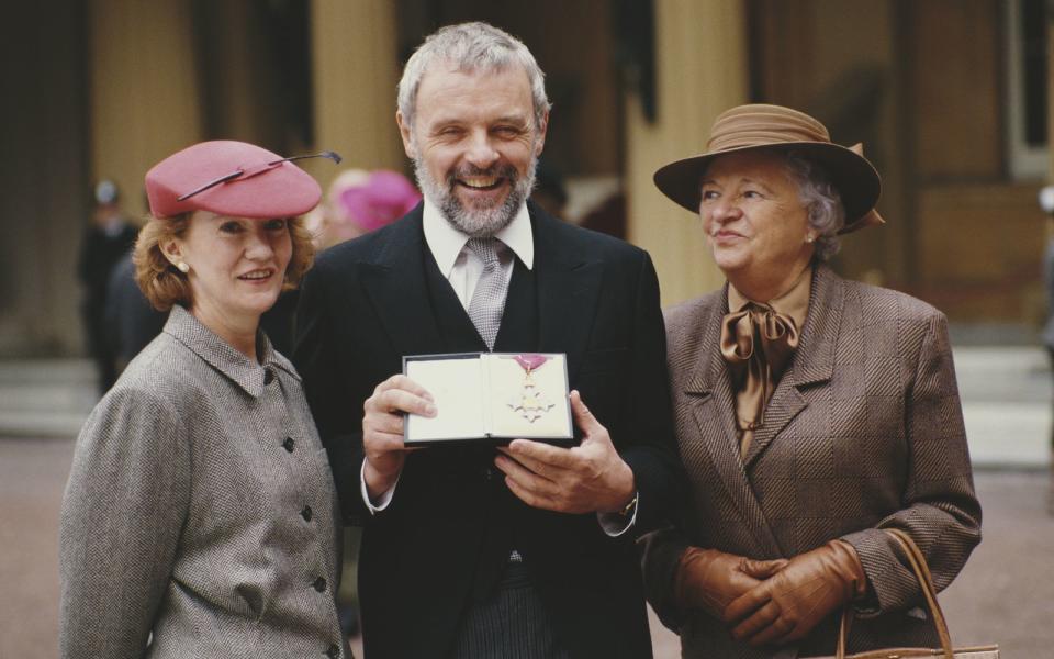 Tom Jones lässt sich abschmatzen, er hingegen brachte nebst Ehefrau Jennifer (links) auch seine Mutter (Annie) mit: 1987 wurde Anthony Hopkins zum "Commander of the Order of the British Empire" ernannt. 1993, zwei Jahre nach seinem Auftritt als Hannibal Lecter in "Das Schweigen der Lämmer", wurde er dann zum "Knight Bachelor". Seitdem heißt es "Sir Anthony Hopkins". (Bild: Fox Photos/Hulton Archive/Getty Images)