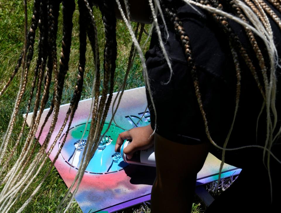 Amina Wilson, 12, of Canal Winchester, spray paints a sign during the first annual Juneteenth on the Avenue on Saturday along Mount Vernon Avenue in Columbus.