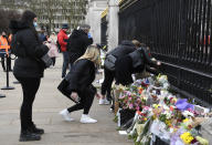 People leave flowers outside the gates of Buckingham Palace in London, a day after the death of Britain's Prince Philip, Saturday, April 10, 2021. Britain's Prince Philip, the irascible and tough-minded husband of Queen Elizabeth II who spent more than seven decades supporting his wife in a role that mostly defined his life, died on Friday. (AP Photo/Alberto Pezzali)