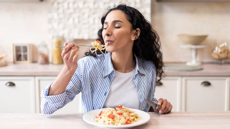 Woman savoring bite of pasta