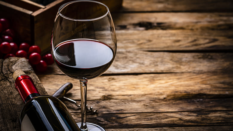 Glass of red wine with bottle and berries