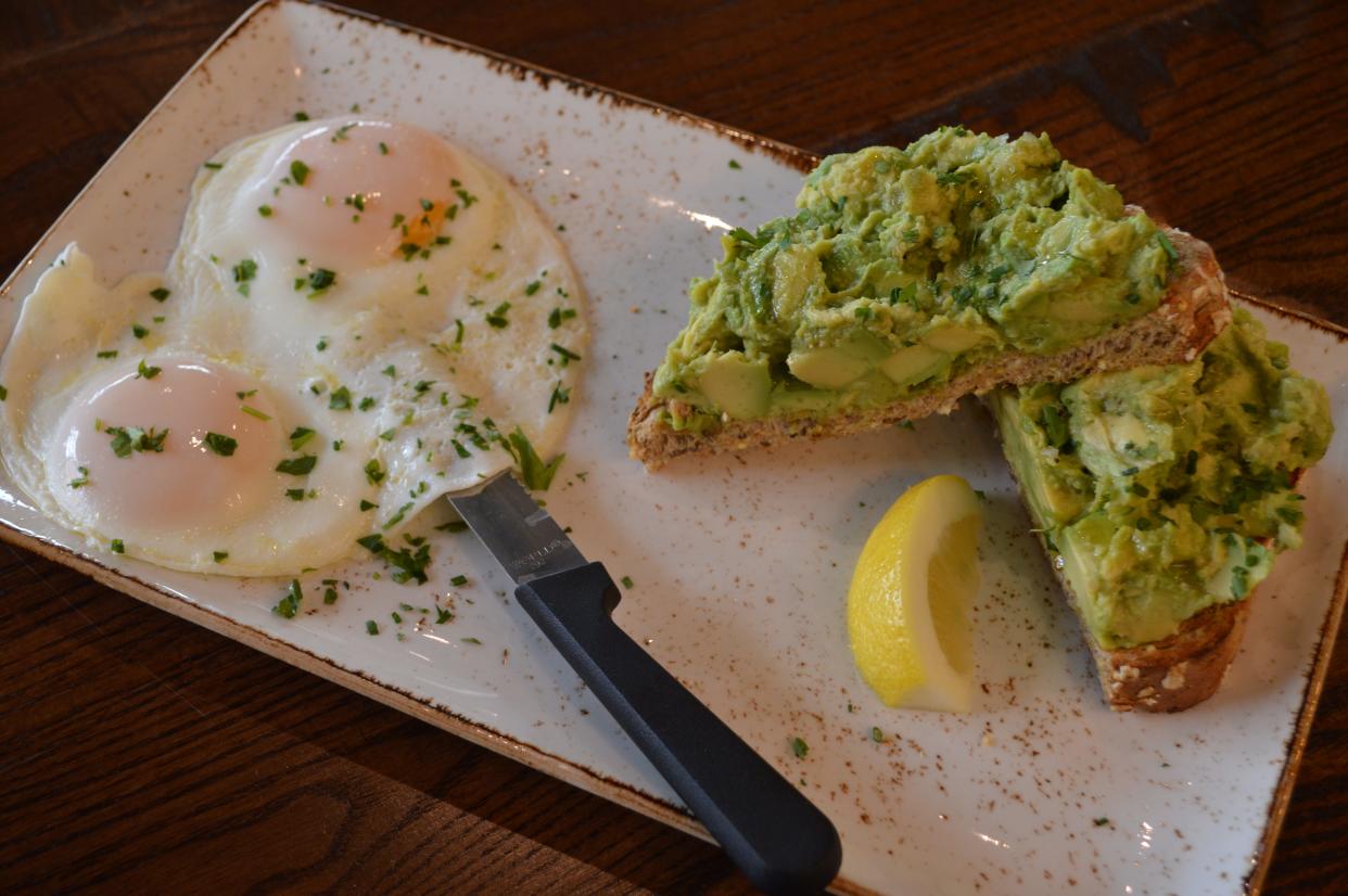 The Avocado Toast at First Watch features thick-cut whole grain artisan toast, fresh smashed avocado, EVOO, lemon and Maldon sea salt with two cage-free basted eggs.