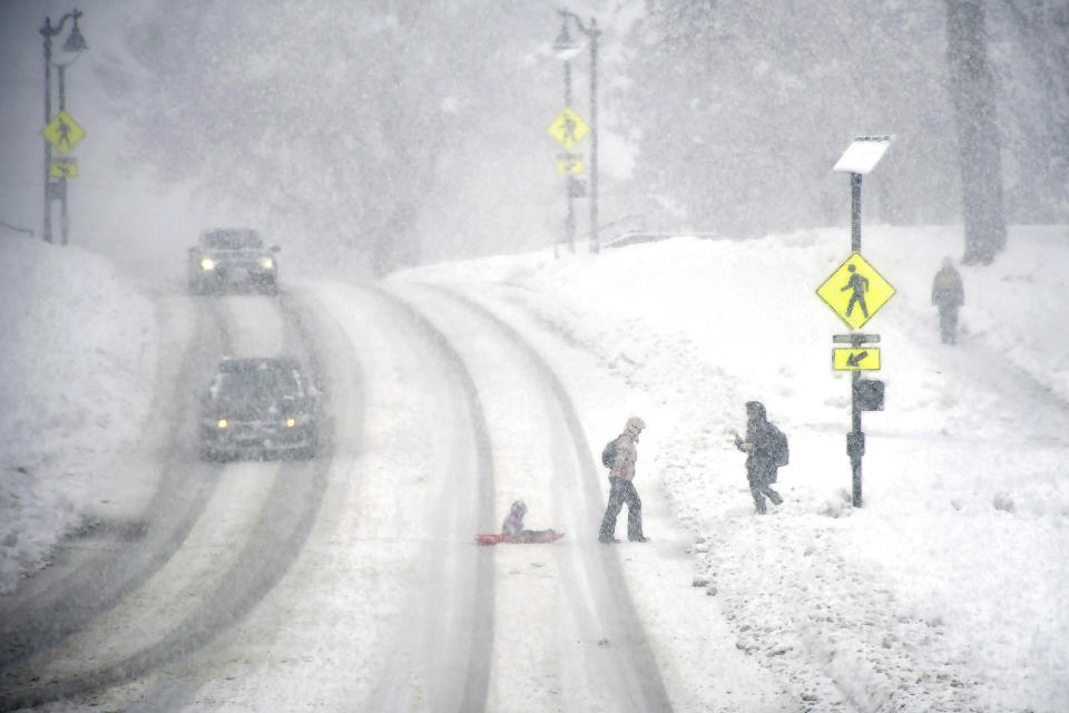 Pulling a sled with a child on board, a woman crosses Main Street in Williamstown, Mass., near the Williams College campus during a snowstorm on Tuesday, March 14 2023. (Gillian Jones/The Berkshire Eagle via AP)