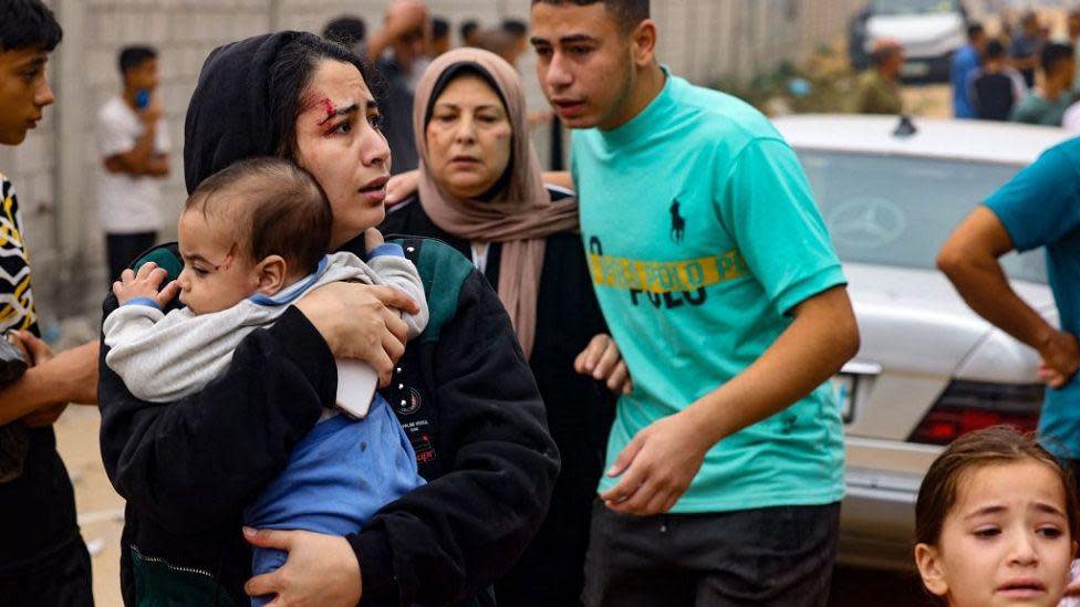 Una mujer con un bebé en brazos huyendo con otros civiles