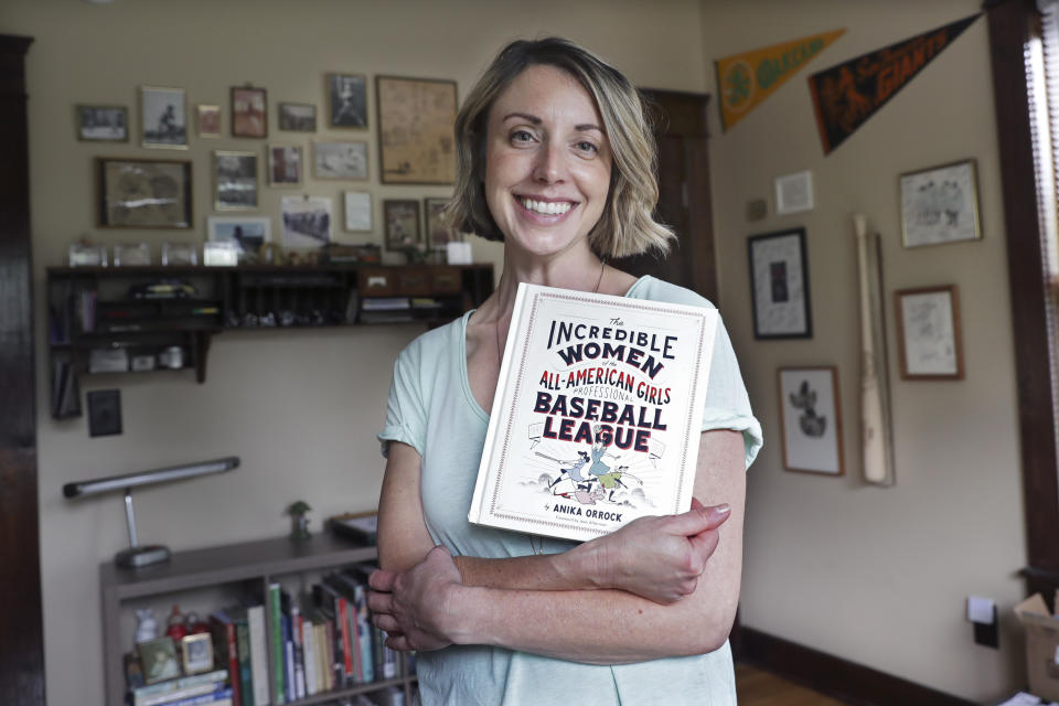 This April 30, 2020, photo shows Anika Orrock with her book "The Incredible Women of the All-American Girls Professional Baseball League" in her home in Nashville, Tenn. Because of the coronavirus pandemic, Orrock's appearance to throw out the first pitch at Yankee Stadium May 5 has been canceled, as well as her plans to travel for the book's promotion. (AP Photo/Mark Humphrey)