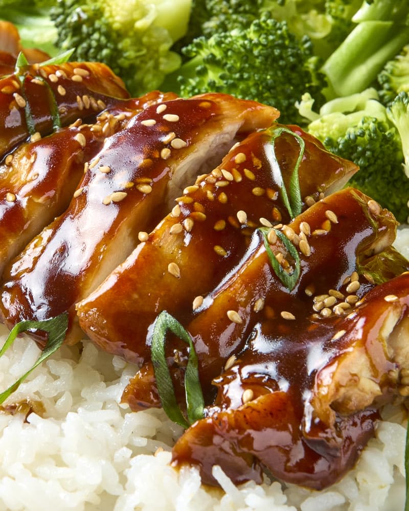 overhead shot of chicken teriyaki served over white rice with a side of broccoli, topped with sesame seeds and green onion