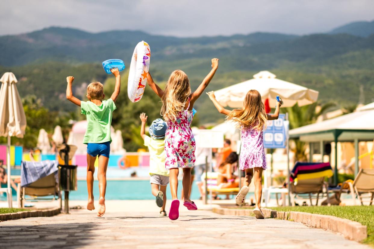 rear view happy kids running to the pool at resort