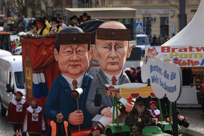 The float "Boards that mean the world", with Russian President Vladimir Putin, Chinese President Xi Jinping and Iranian Supreme Leader Ali Khamenei, moves during the Rose Monday parade in Cologne. Oliver Berg/dpa