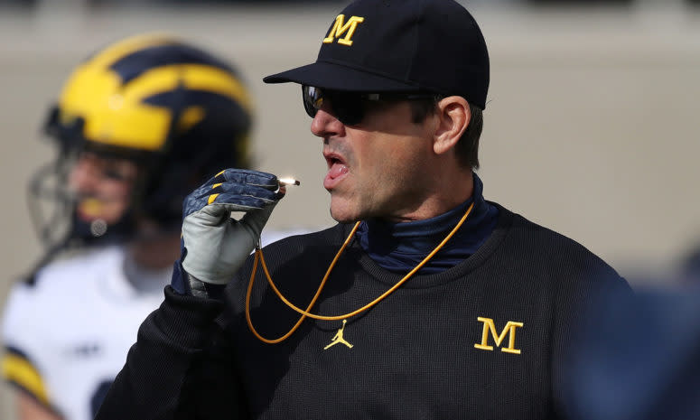 Jim Harbaugh putting a whistle in his mouth.