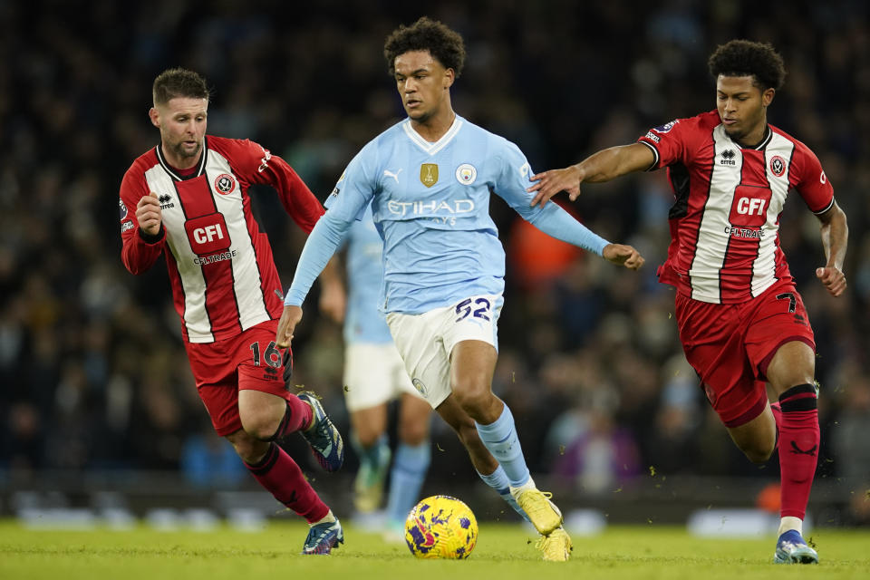 Oscar Bobb del Manchester City pelea por el balón con Oliver Norwood y Rhian Brewster del Sheffield United en el encuentro de la Liga Premier el sábado 30 de diciembre del 2023. (AP Foto/Dave Thompson)