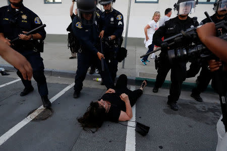 A woman falls as police officers move the line during a demonstration against Republican U.S. presidential candidate Donald Trump outside his campaign event in San Jose, California, U.S. June 2, 2016. REUTERS/Stephen Lam