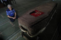 The father of Ibrahim Harb, 35, a Lebanese man who was critically injured in the massive explosion at Beirut's port last year and who died on Monday nearly 14 months after the blast, prays at a mosque at his son's coffin in Beirut, Lebanon, Tuesday, Sept. 28, 2021. On Aug. 4, 2020, hundreds of tons of ammonium nitrate, a highly explosive material used in fertilizers, ignited after a massive fire at the port. The death brings to at least 215 the number of people who have been killed by the blast, according to official records. (AP Photo/Hussein Malla)