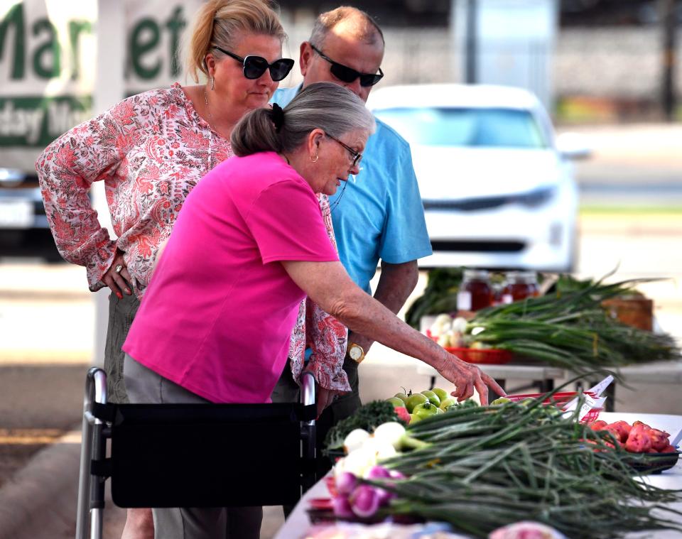 Giny Franklin looks over a selection of fresh vegetables with her daughter Dana Villarreal and Joe Arroyo during a morning outing to the Abilene Farmer's Market May 14.