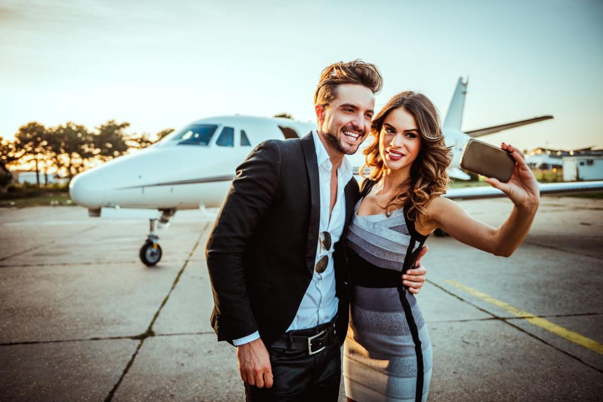 A couple taking a picture while outside of a private jet.