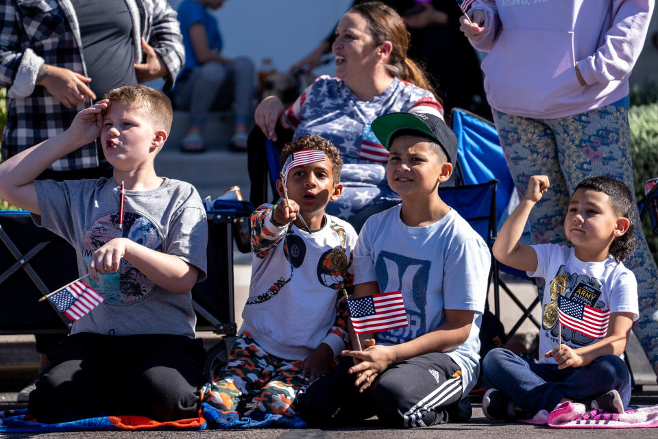 Aidan Day, 11, left, David Brown, 9, second from left, Israel Garcia, 10, second from right, and Mathias Garcia, 5, right, cheer during a Veterans Day parade in Phoenix on Nov. 11, 2022.