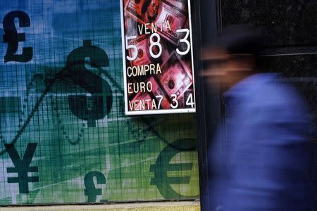 A pedestrian walks past a money exchange bureau with a board displaying the exchange rate of the U.S. dollar against the Chilean Peso, in downtown Santiago October 30, 2014. REUTERS/Ivan Alvarado