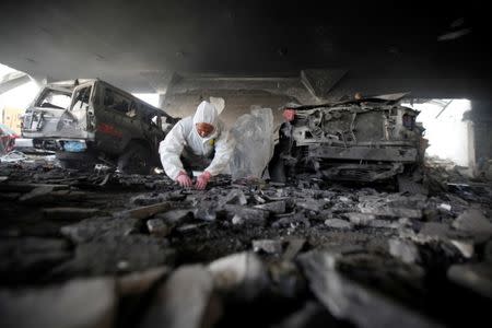 A forensic expert invistigates the scene at the community hall where Saudi-led warplanes struck a funeral in Sanaa, the capital of Yemen. REUTERS/Khaled Abdullah