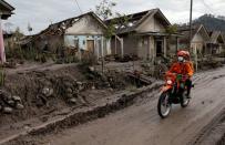 Rescue workers ride a motorcycle through an area affected by the eruption of Mount Semeru volcano in Curah Kobokan village, Pronojiwo district, in Lumajang, Indonesia