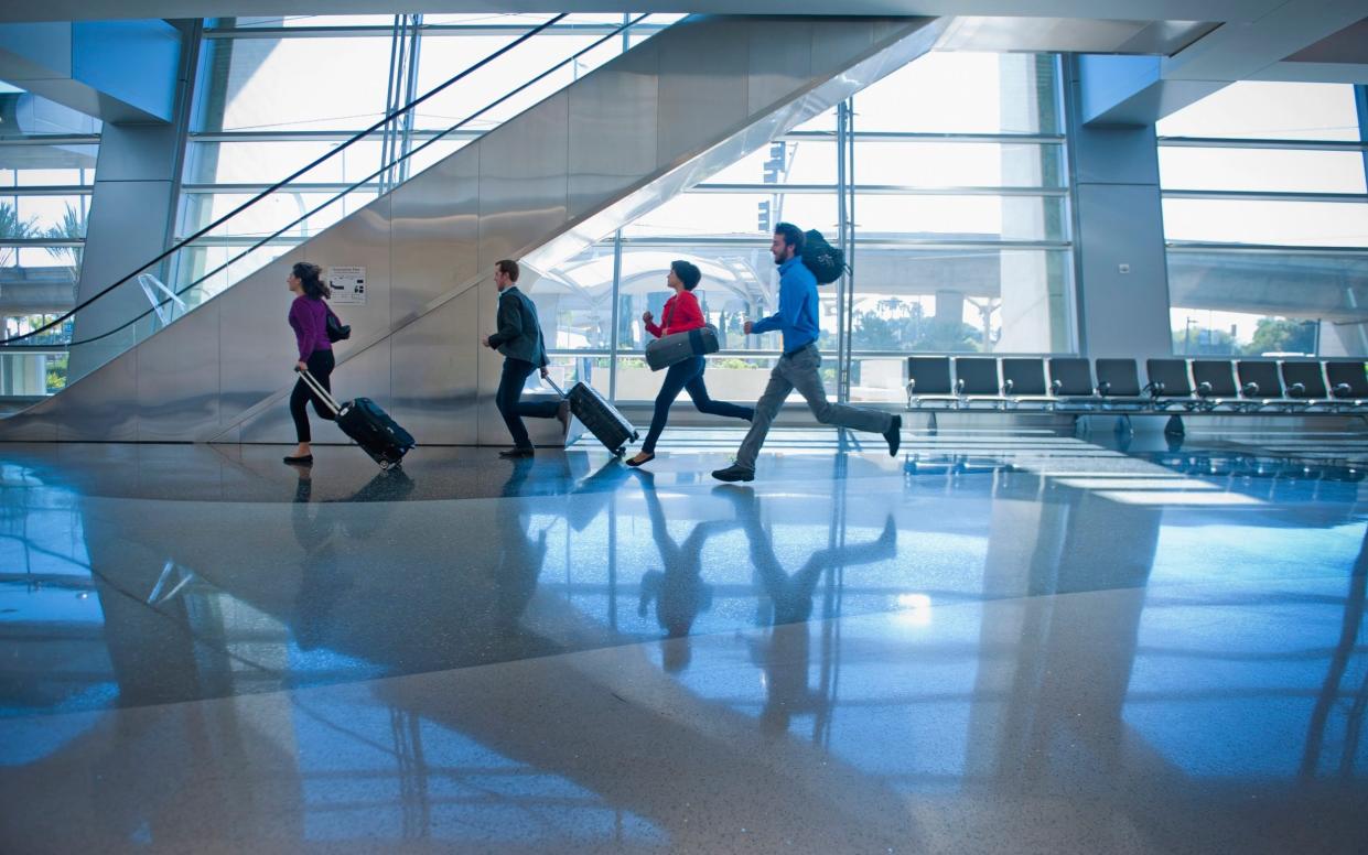 People running with wheelie suitcases at the airport