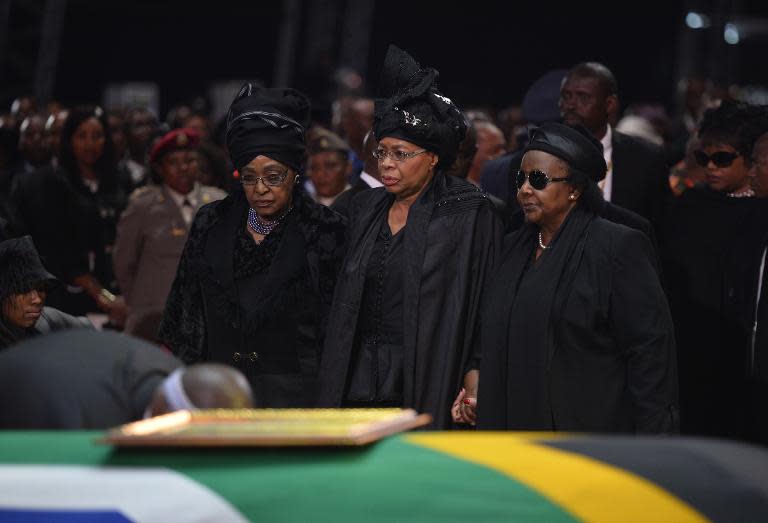 Winnie Mandela Madikizela (L) and Graca Machel (C) stand by the coffin of Nelson Mandela during his funeral ceremony in Qunu on December 15, 2013