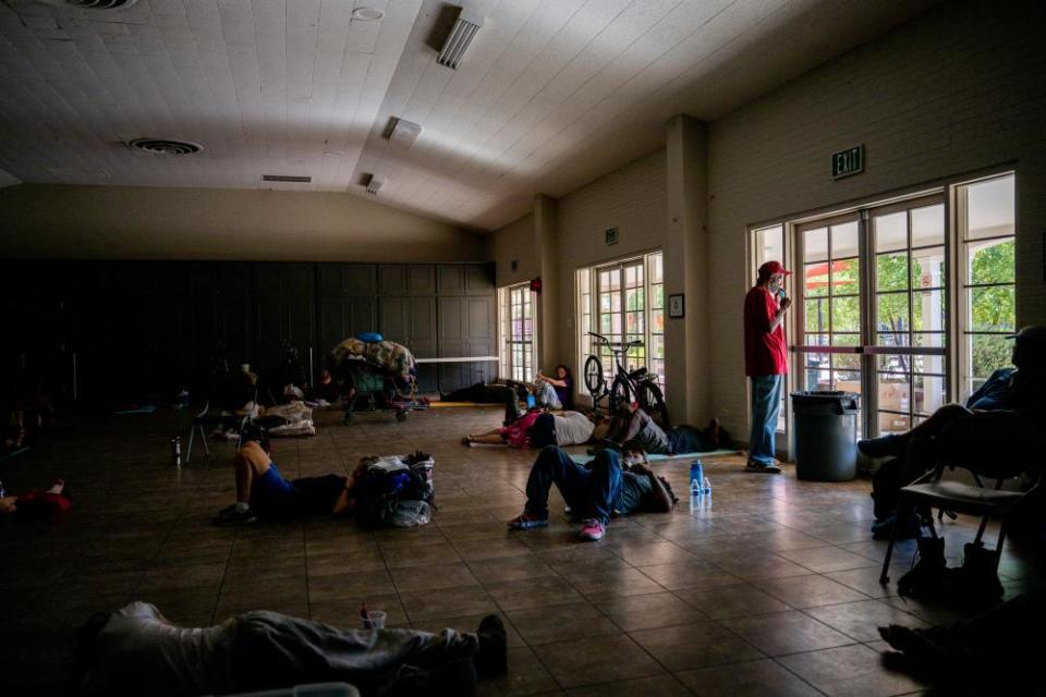 A person stands eating a popsicle while looking out of a window at the First Congregational United Church of Christ shelter in Phoenix, Arizona.