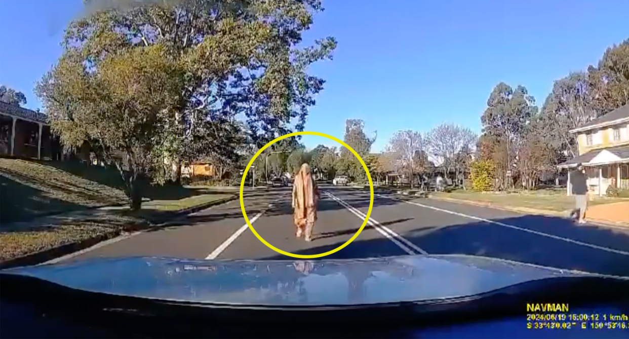 A woman caught on dash cam walking towards the car in the middle of a Sydney road.