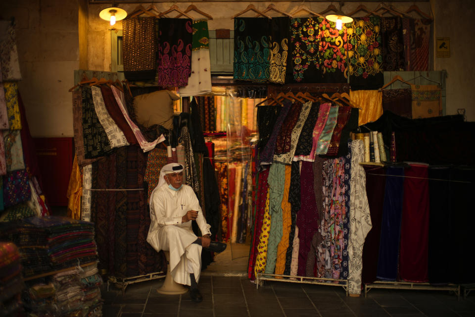 A clothes shop seller drinks tea as he waits for customers in Souq Waqif market, one day ahead of the World Cup kick off, in Doha, Qatar, Saturday, Nov. 19, 2022. (AP Photo/Francisco Seco)