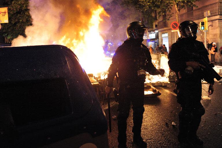 Riot police stand near burning bin containers in Barcelona on May 28, 2014 on the third night of clashes following evictions of activists