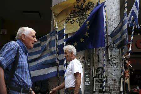 People make their way next to Greek national flags and a European Union flag in Athens, August 27, 2015. REUTERS/Alkis Konstantinidis