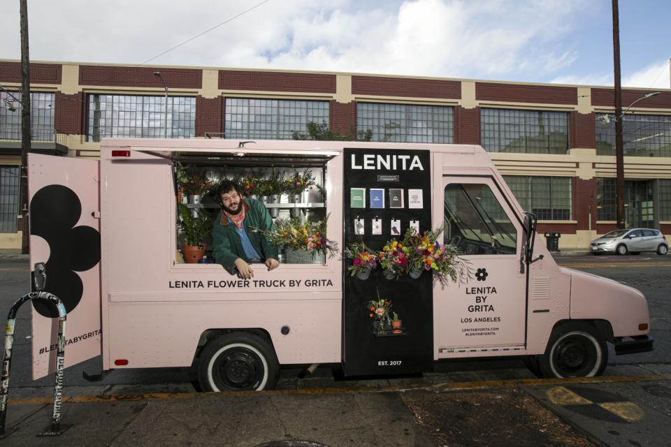 Nemuel DePaula leans out the window of his pink flower truck.