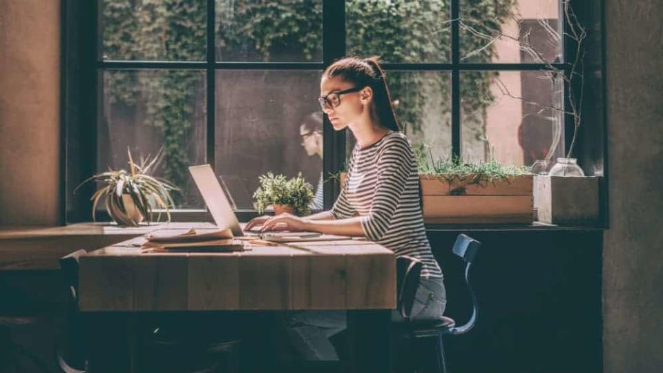 Young woman sat at laptop by a window