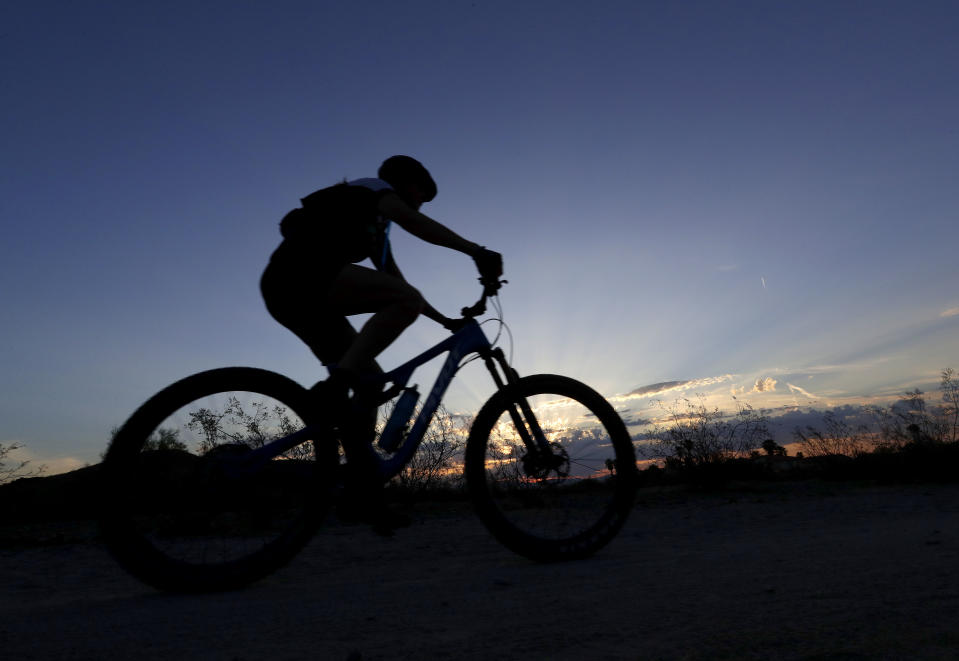 A biker hits the trail at dawn to beat the heat Tuesday, July 24, 2018 in Phoenix. Much of Arizona and parts of California, Arizona and Utah are under an excessive heat watch during a week that forecasters say could prove to be the hottest of the year. (AP Photo/Matt York)