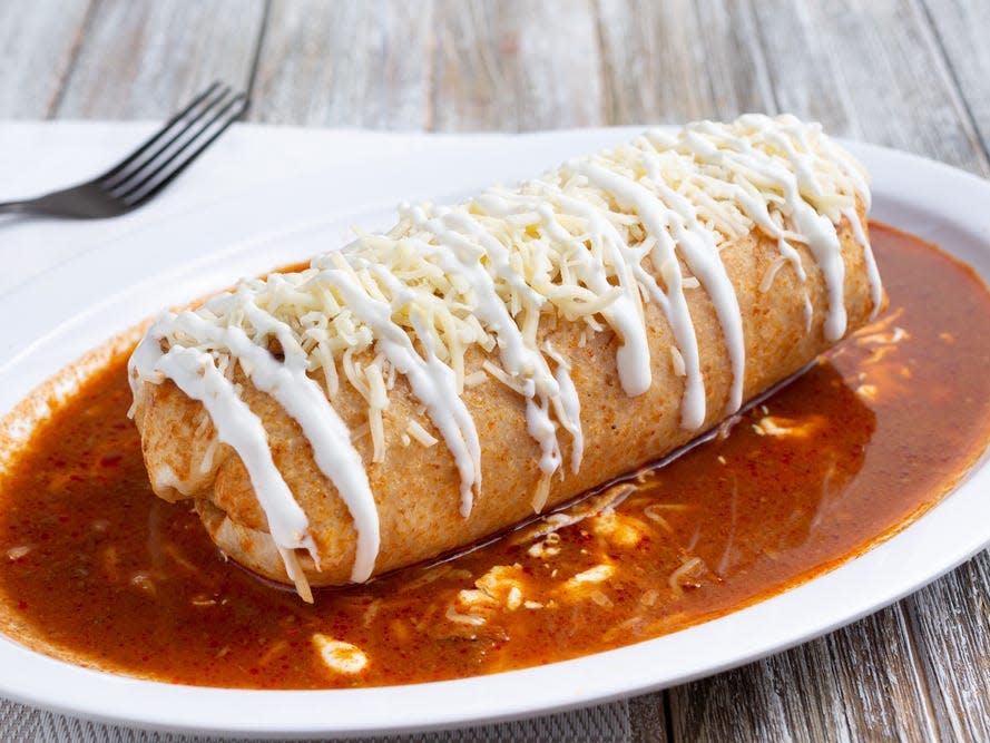 wet burrito covered in sour cream and salsa on a plate