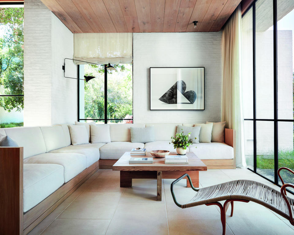 family room with white brick walls, limestone flags, built in wooden seating with white cushions, coffee table and vintage lounge chair