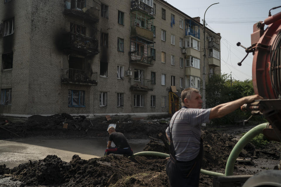 Trabajadores sacan agua de un cráter causado por una explosión que dañó un edificio residencial luego de un ataque ruso en Slovyansk, Ucrania, el domingo 28 de agosto de 2022. (AP Foto/Leo Correa)