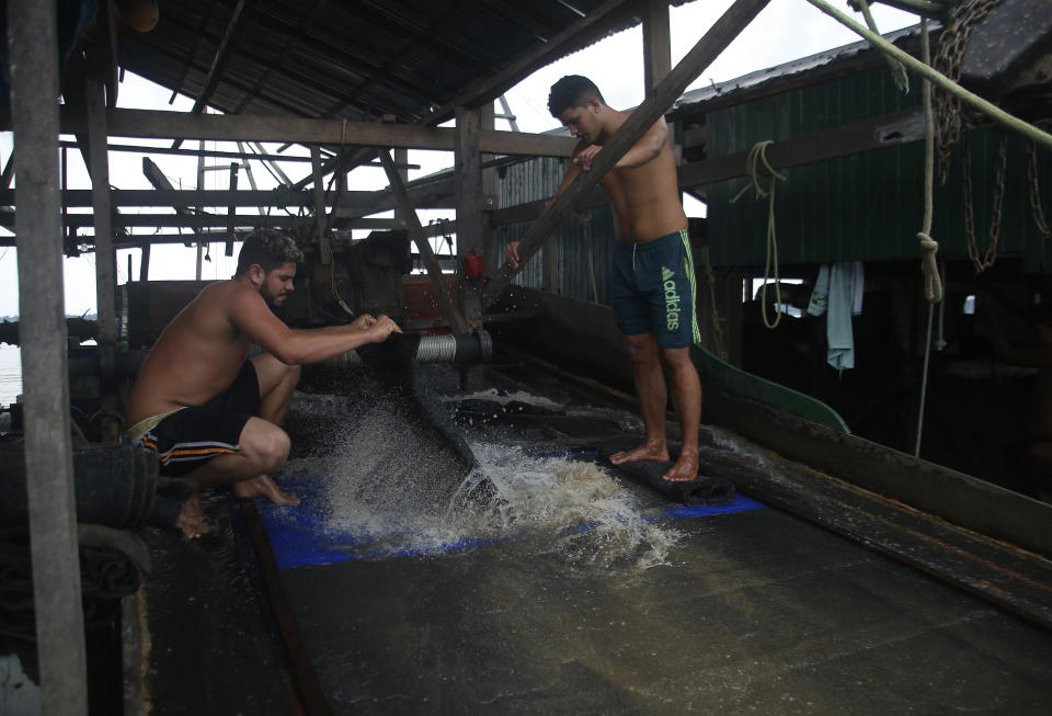 Illegal gold miners work on a dredging barge on the Madeira river, a tributary of the Amazon river, searching for gold, in Autazes, Amazonas state, Brazil, Thursday, Nov.25, 2021. Hundreds of mining barges have arrived during the past two weeks after rumors of gold spread, with environmentalists sounding the alarm about the unprecedented convergence of boats in the sensitive ecosystem. (AP Photo/Edmar Barros)