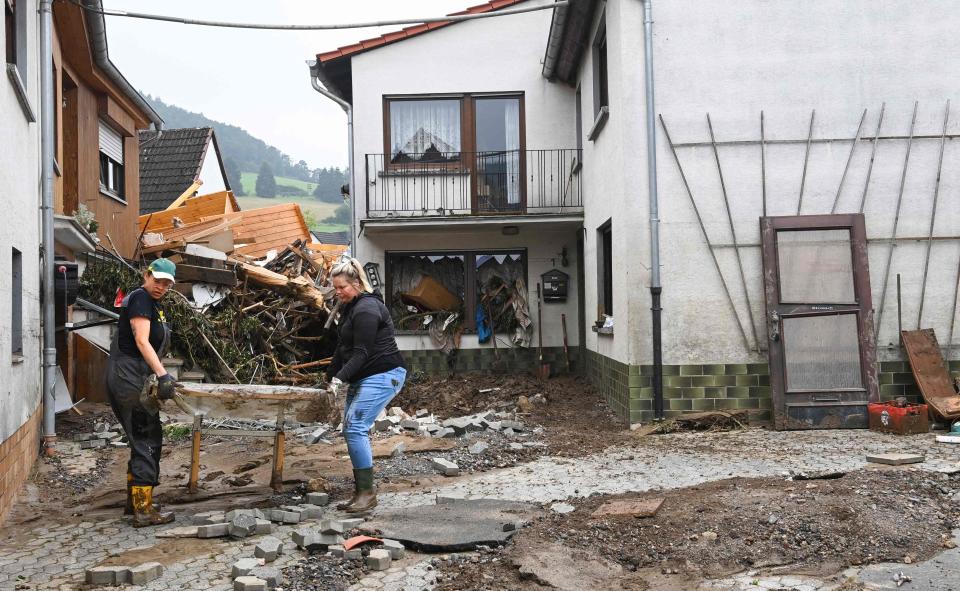 Residents carry destroyed and muddy belongings out of a house after the floods caused major damage in Schuld near Bad Neuenahr-Ahrweiler, western Germany, on July 17, 2021. - Devastating floods in Germany and other parts of western Europe have been described as a 