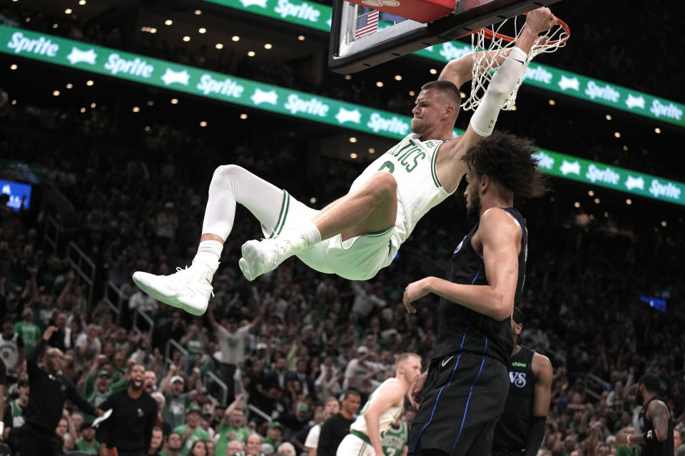 Boston Celtics center Kristaps Porzingis dunks next to Dallas Mavericks center Dereck Lively II, foreground, during the first half of Game 1 of basketball's NBA Finals on Thursday, June 6, 2024, in Boston. (AP Photo/Charles Krupa)